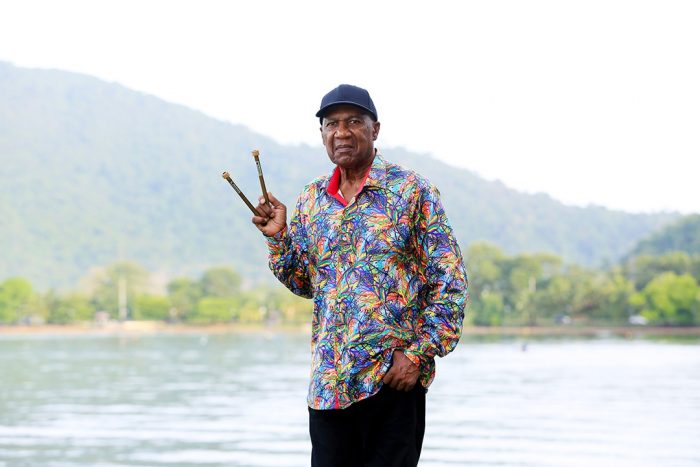 Len "Boogsie" Sharpe poses with mallets in hand in front of a lake. 