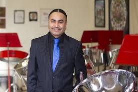 Liam Teague poses next to the NIU Steel Orchestra steelpans. 